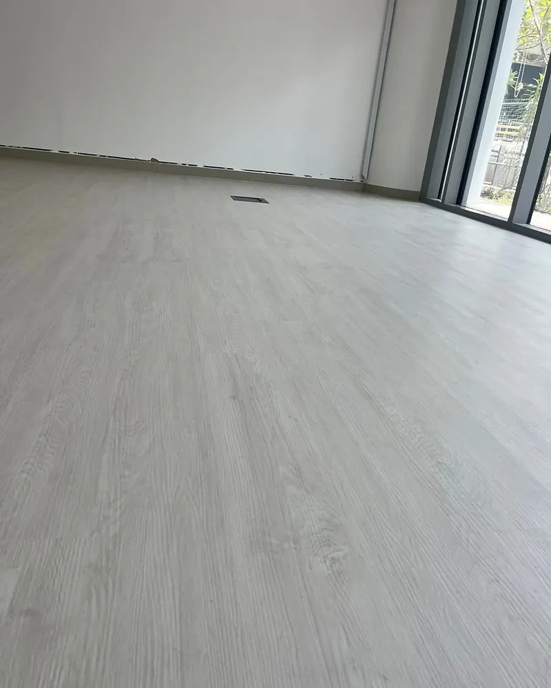 Installer fitting light-grey SPC planks in an empty unit