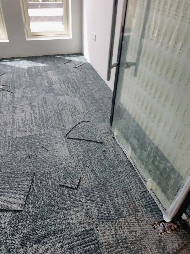 Office carpet tiles being laid beside a glass partition