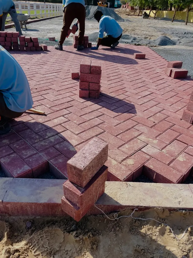 Anas Technical Services crew in company uniform laying interlock pavers on site