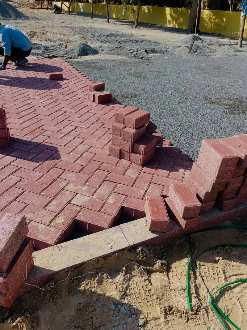 Crew laying red interlock pavers — detail