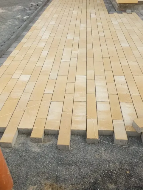 Yellow interlock pavers being laid, villa driveway — detail