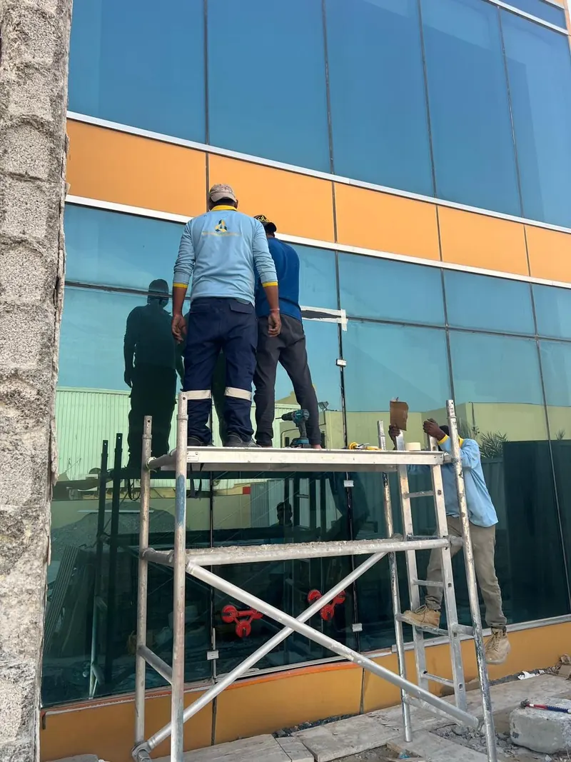 Workers on scaffold fitting curtain wall glazing, DIP 2
