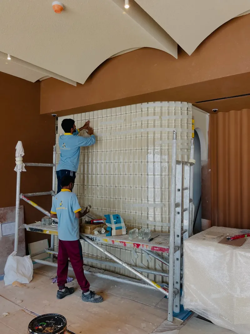 Worker on a scaffold building a curved glass block wall