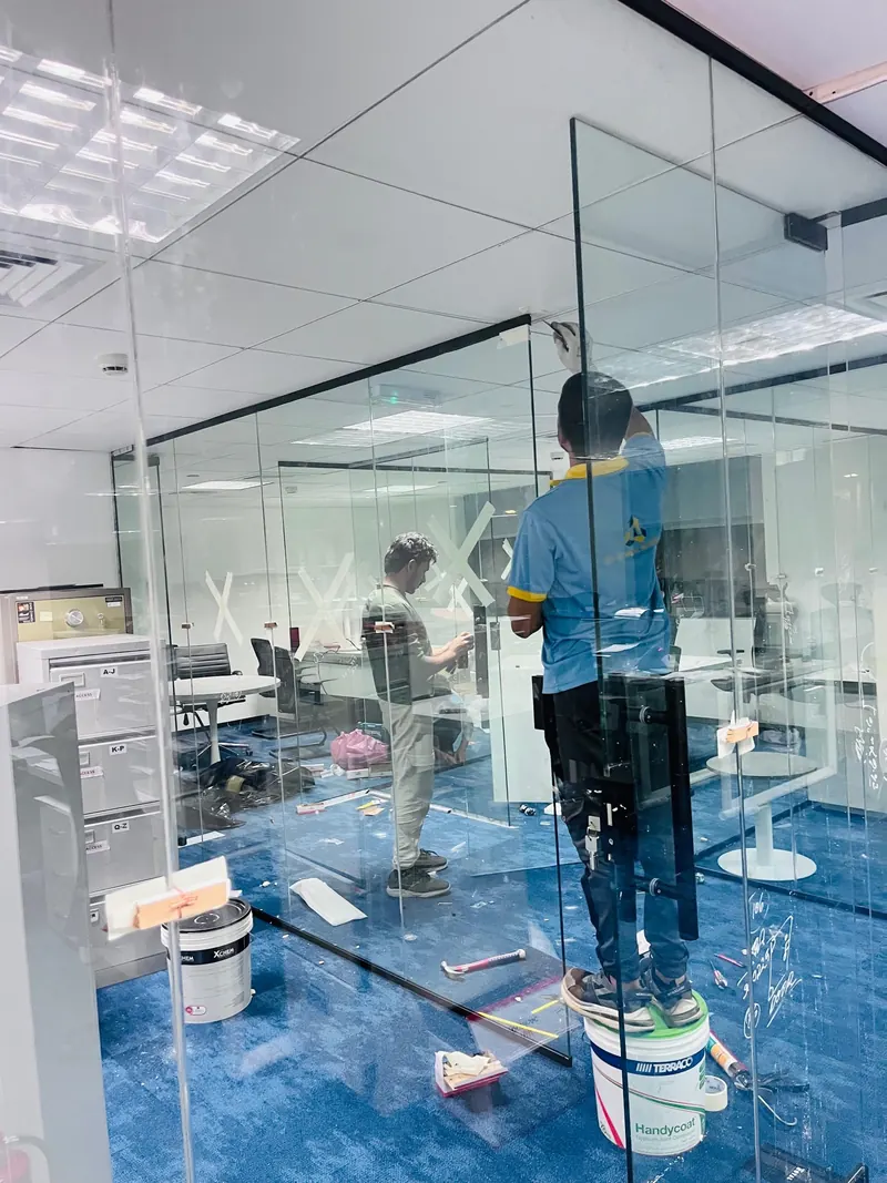 Worker fitting a frameless glass office partition