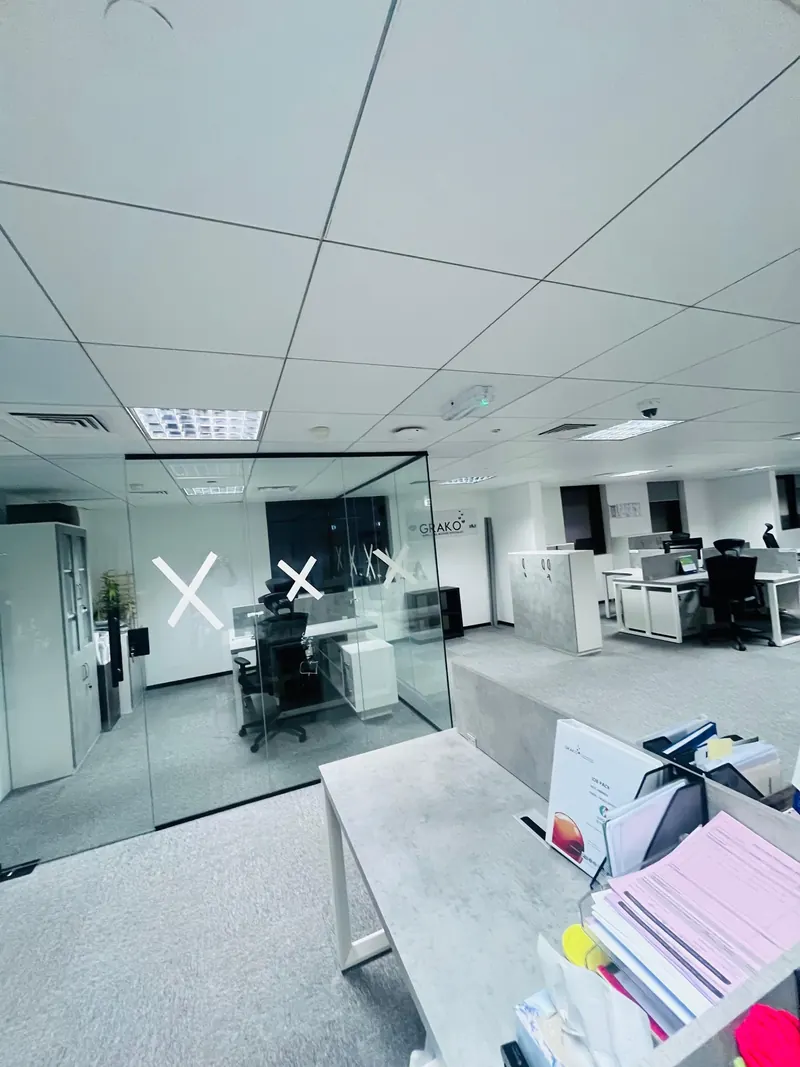 Completed frameless glass office partitions with a worker finishing the installation
